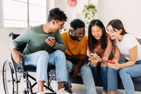Group of diverse teenage people using smart mobile phone together at home Stock Photos