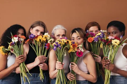Group of diverse women hide their faces by bouquets of flowers Stock Photos