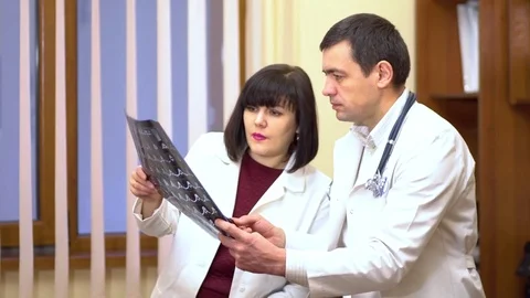 A group of doctors is considering an x-ray. Women and a man. They lead the Stock Footage 74252889
