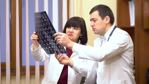 A group of doctors is considering an x-ray. Women and a man. They lead the Video stock 74253176