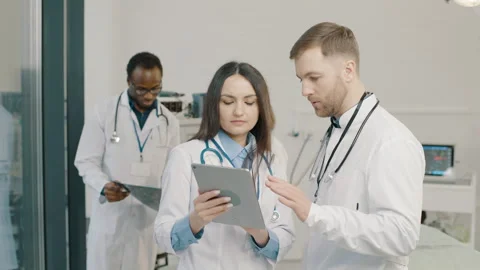 A group of doctors examine a patient's tests on a tablet in a medical clinic Stock Footage 265272360