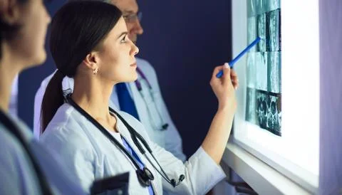 Group of doctors examining x-rays in a clinic, thinking of a diagnosis Stock Photos