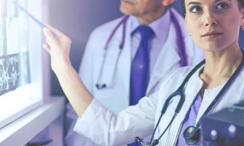 Group of doctors examining x-rays in a clinic, thinking of a diagnosis Stock Photos