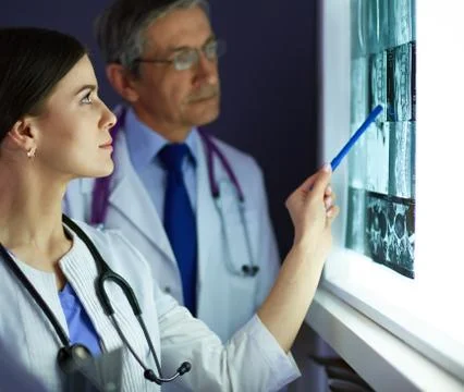 Group of doctors examining x-rays in a clinic, thinking of a diagnosis Stock Photos