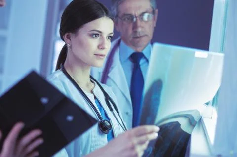 Group of doctors examining x-rays in a clinic, thinking of a diagnosis Stock Photos