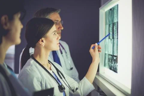 Group of doctors examining x-rays in a clinic, thinking of a diagnosis Stock Photos