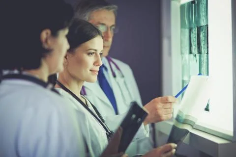 Group of doctors examining x-rays in a clinic, thinking of a diagnosis Stock Photos