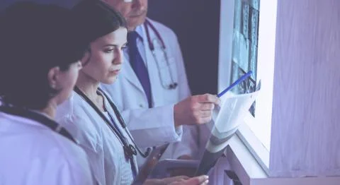 Group of doctors examining x-rays in a clinic, thinking of a diagnosis Stock Photos