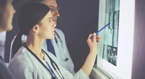 Group of doctors examining x-rays in a clinic, thinking of a diagnosis Stock Photos