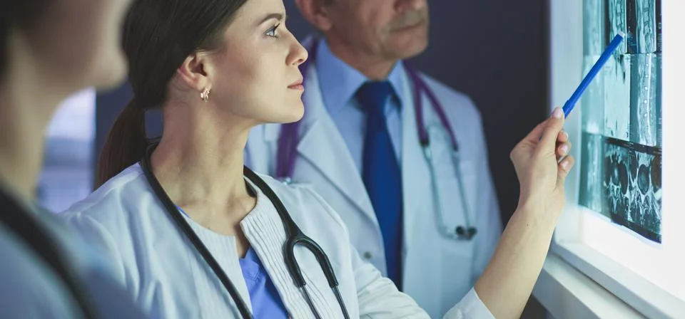 Group of doctors examining x-rays in a clinic, thinking of a diagnosis Stock Photos