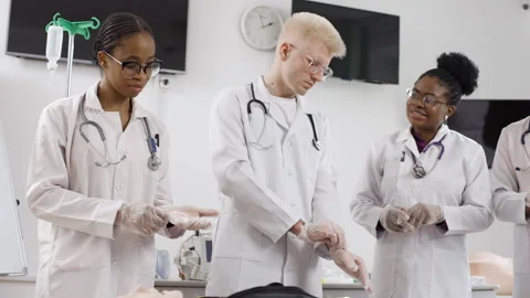 Group of doctors at a first aid course put on medical gloves in clinic Stock Footage 270168074