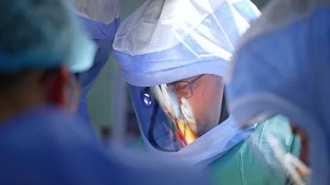 Group of doctors in helmets cooperate at surgery.  Stock Footage 307429903