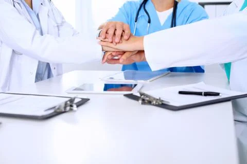 Group of doctors joining hands after  meeting. Succesful medical team is read Stockfoto's
