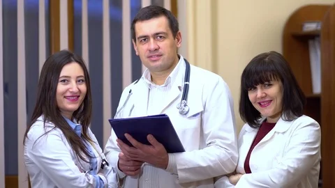 Group of doctors looking at camera and smiling. Male doctor keep a tablet Stock Footage 74255696
