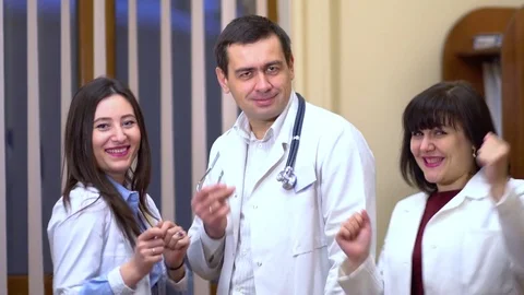 A group of doctors looking at the camera and dancing. Two women and a man Stock Footage 74256294