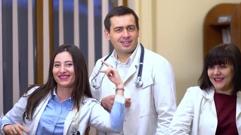 A group of doctors looking at the camera and dancing. Two women and a man Stock Footage 74256526