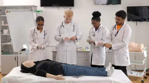Group of doctors standing at the bed with mannequin at first aid training course Stock Footage 275946387