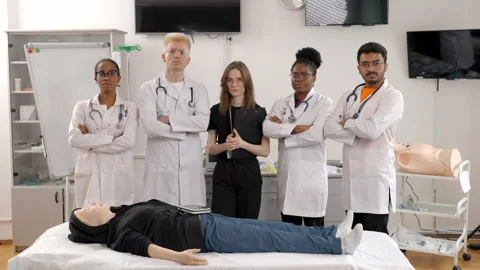 Group of doctors standing at the bed with mannequin at first aid training course Stock Footage 316169784
