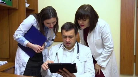 A group of doctors talking. Two women and a man. Male doctor keep a tablet Stock Footage 74251044