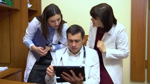 A group of doctors talking. Two women and a man. Male doctor keep a tablet Stock Footage 74251398