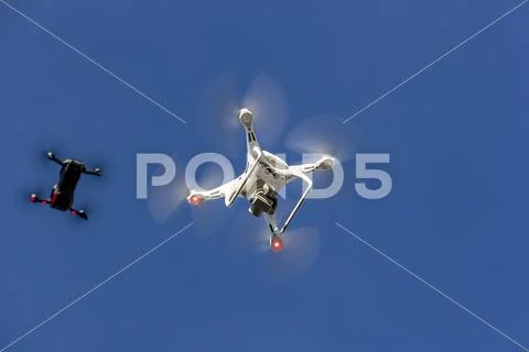 A Group Of Drones Fly Together Through The Air Against A Blue Sky Stock Photos