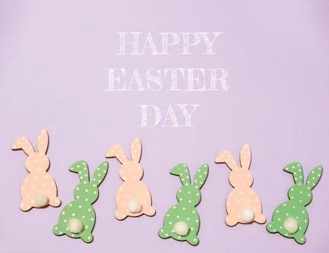 Group of Easter bunny figurines are arranged in a row on a purple background Stockfoto's