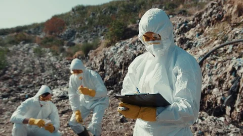 Group of ecologists working on dump evaluating pollution damage. Two male Video stock 113930142