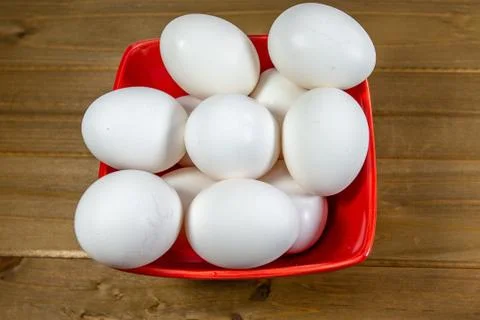A group of eggs inside a deep red bowl waiting for the chef Foto stock