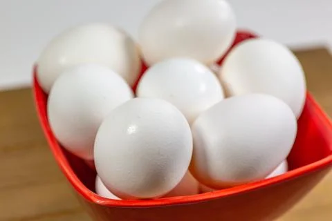 A group of eggs inside a deep red bowl waiting for the chef Stock Photos
