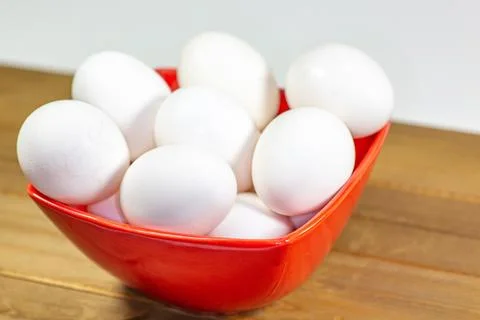 A group of eggs inside a deep red bowl waiting for the chef Stock Photos