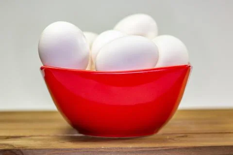 A group of eggs inside a deep red bowl waiting for the chef Stock Photos