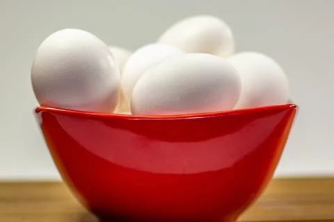 A group of eggs inside a deep red bowl waiting for the chef Stock Photos