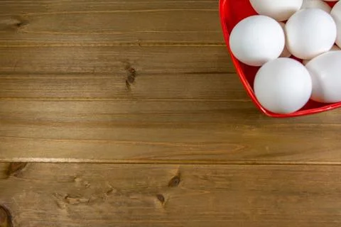 A group of eggs inside a deep red bowl waiting for the chef Stock Photos