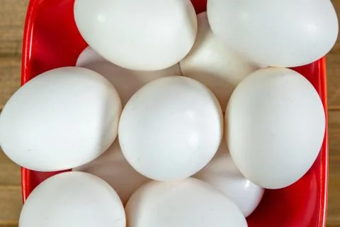 A group of eggs inside a deep red bowl waiting for the chef Stock Photos