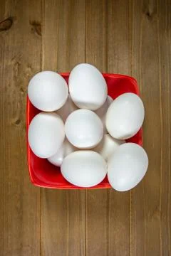 A group of eggs inside a deep red bowl waiting for the chef Stock Photos