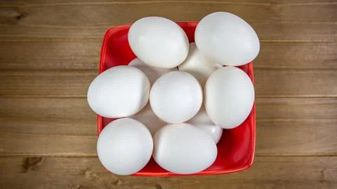 A group of eggs inside a deep red bowl waiting for the chef Stock Photos