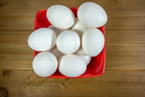 A group of eggs inside a deep red bowl waiting for the chef Foto stock