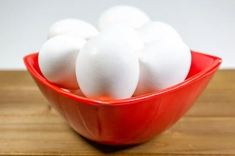 A group of eggs inside a deep red bowl waiting for the chef Stock Photos