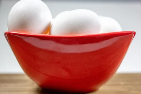 A group of eggs inside a deep red bowl waiting for the chef Stock Photos