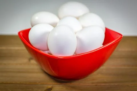 A group of eggs inside a deep red bowl waiting for the chef Stock Photos