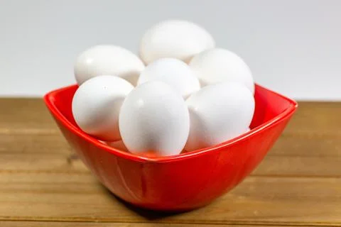 A group of eggs inside a deep red bowl waiting for the chef Stock Photos