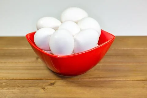A group of eggs inside a deep red bowl waiting for the chef Foto stock