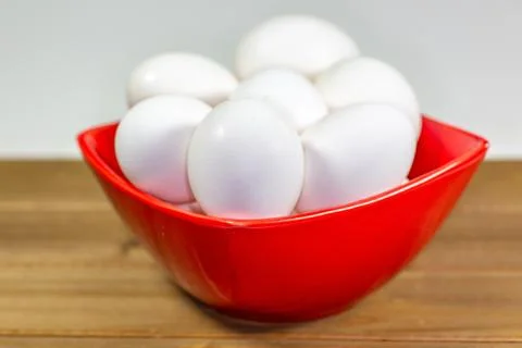A group of eggs inside a deep red bowl waiting for the chef Stock Photos