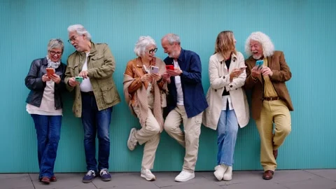 Group of elderly Caucasian laughing together using cell phone standing leaning Stock Footage 275247657