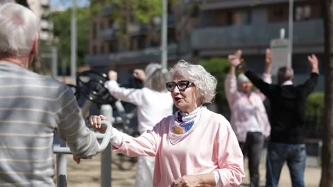 Group of elderly people exercising using equipment in courtyard Stock Footage 343719465