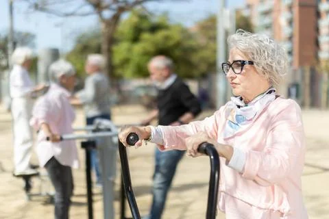 Group of elderly people exercising using equipment in courtyard Stock Photos