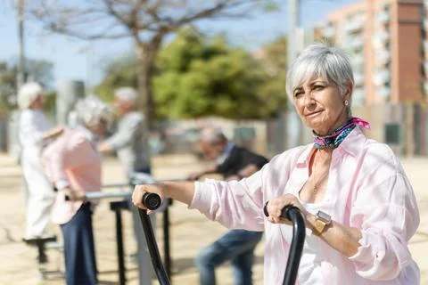Group of elderly people exercising using equipment in courtyard Stock Photos