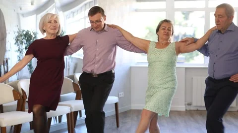 Group of elderly people with middle-aged man perform Irish folk dance Stock Footage 303669818