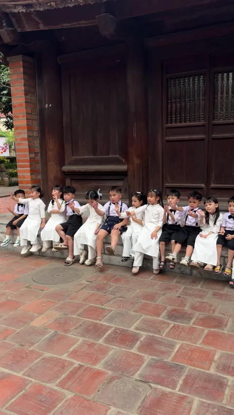 Group of elementary school children in uniform sitting together outdoors 스톡 동영상 341132767