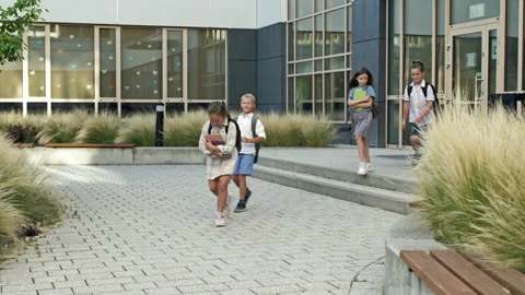 Group of elementary school students joyfully run out of the school building. End Video stock 204069000